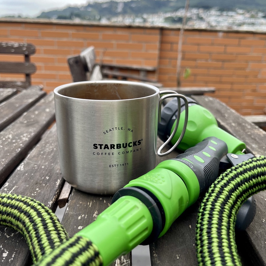 Coffee cup and watering hose on top of a table - Braga Rooftop (RUG)